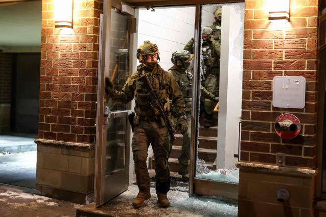 Federal agents with Homeland Security Investigations (HSI) exit a residential building as they seek to detain a protestor in Minneapolis, Minnesota, on February 5, 2026. US President Donald Trump suggested on February 4 that a "softer touch" may be needed on immigration, as his administration said 700 federal officers would be pulled from Minnesota but that mass deportations would not stop. The fatal shootings of two protesters by federal officers in Minneapolis last month sparked widespread outrage in the United States and calls for an end to immigration raids in the Midwestern city, but Trump's administration has been reluctant to shift course. (Photo by CHARLY TRIBALLEAU / AFP)