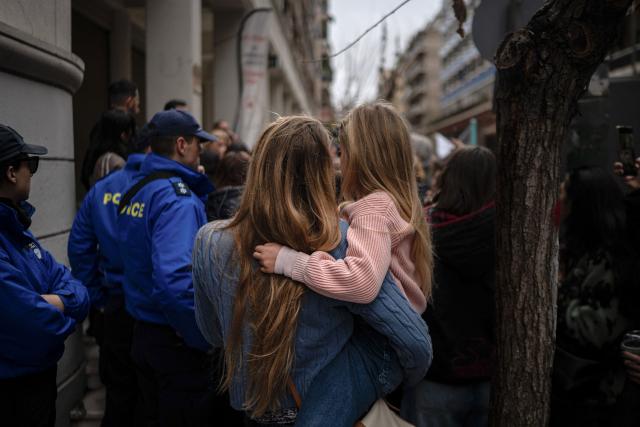 mother holds her child in her arms during a protest of midwives against new restrictions in front of the Ministry of health in Athens, on February 5, 2026. Hundreds of midwives protested in Athens over new restrictions on how they work in hospitals that mean they will not be able to deliver babies without a doctor's supervision. (Photo by Angelos TZORTZINIS / AFP)