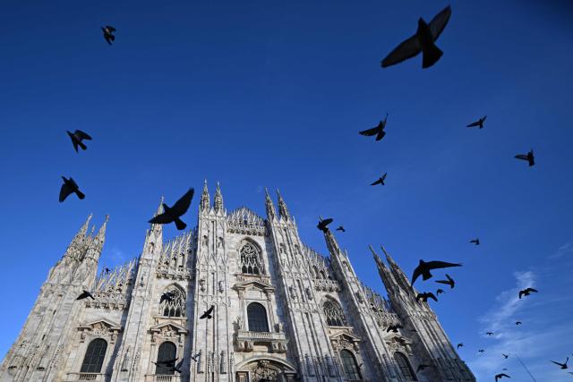 Pigeons fly at Piazza Duomo in central Milan ahead of Milano Cortina 2026 Olympic Games, on February 5, 2026. (Photo by Daniel MUNOZ / AFP)