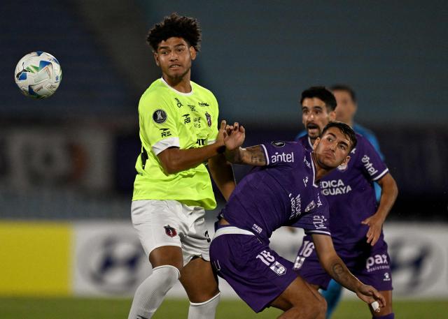 (FILES) Monagas' defender #34 Yulwuis Perez and Defensor Sporting's forward #19 Diego Abreu fight for the ball during the Copa Libertadores qualification first round second leg football match between Uruguay's Defensor Sporting and Venezuela's Monagas at the Centenario stadium in Montevideo, on February 11, 2025. Tijuana's Uruguayan coach Sebastian ‘El Loco’ Abreu,  will send his son Diego onto the pitch, an eagerly awaited debut in the 2026 Clausura. Diego, 22, a recent arrival from Uruguayan football, could make his debut in Mexico this weekend when the Xolos host Puebla on the fifth matchday of the local league. (Photo by Eitan ABRAMOVICH / AFP)