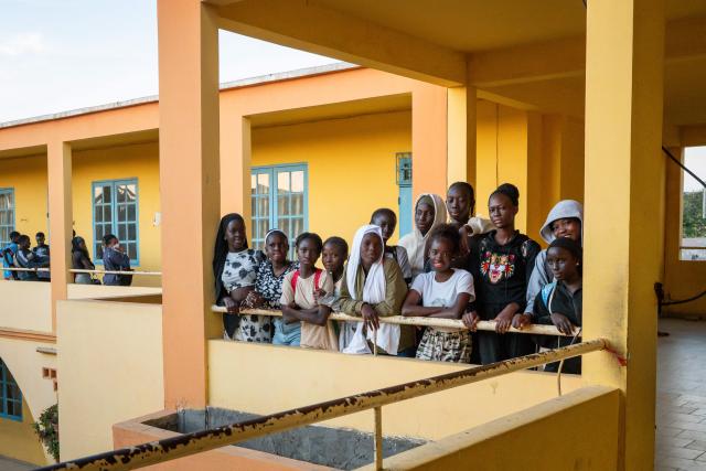 Young girls who are taking part in the Surf Academy program of the Black Girls Surf organization pose in the hallways of Stella Maris Primary School in the Ouakam neighbourhood of Dakar on 29 January 2026, before their compulsory evening classes. School education and course attendance at all levels are an integral part of the surf academy's programme. Some twenty girls coming from the little community of Xataxely, a fishing village of narrow walkways that is part of the capital's larger Ngor neighbourhood, are participating in an inaugural Surf Academy which requires they enroll in school, incentivised by the chance to shred waves -- or at least try. The area is a stronghold of Senegal's Lebou ethnic group, a fishing people closely tied to the ocean who live throughout the Dakar region. Dakar's world-class, year-round waves not only serve as the backdrop to the girls' lives, but also attract surfers from across the globe, including to the famed Ngor Right point break where the girls often practice. (Photo by NICOLAS REMENE / AFP)