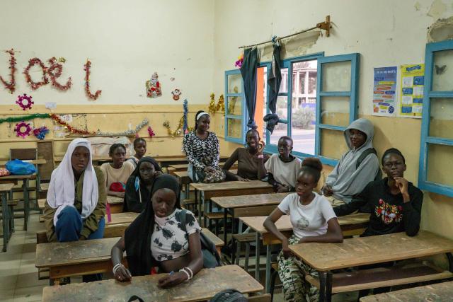 The young girls taking part in the Surf Academy program of the Black Girls Surf organization pose in a classroom at Stella Maris Primary School in the Ouakam district of Dakar on 29 January 2026, before their compulsory evening classes. School education and regular attendance at classes, regardless of level, are an integral part of the surf academy's programme. Some twenty girls coming from the little community of Xataxely, a fishing village of narrow walkways that is part of the capital's larger Ngor neighbourhood, are participating in an inaugural Surf Academy which requires they enroll in school, incentivised by the chance to shred waves -- or at least try. The area is a stronghold of Senegal's Lebou ethnic group, a fishing people closely tied to the ocean who live throughout the Dakar region. Dakar's world-class, year-round waves not only serve as the backdrop to the girls' lives, but also attract surfers from across the globe, including to the famed Ngor Right point break where the girls often practice. (Photo by NICOLAS REMENE / AFP)