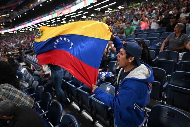 Venezuelan fans wave a national flag as they cheer for their team during a game of the 2026 Series of the Americas between Venezuela's Navegantes del Magallanes and Panama's Aguilas Metropolitanas at the Simon Bolivar Monumental Stadium in Caracas on February 5, 2026. (Photo by Federico PARRA / AFP)