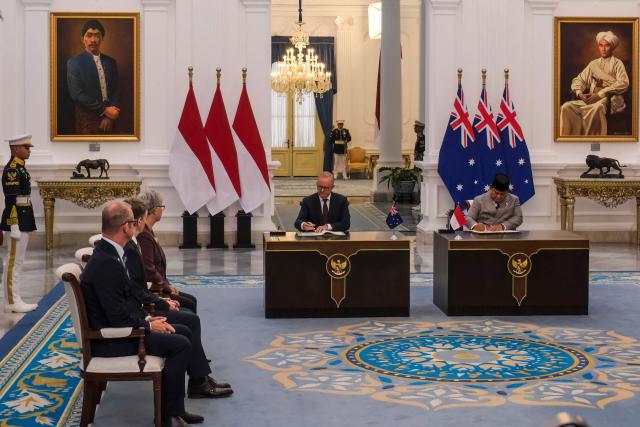 Indonesian President Prabowo Subianto (R) and Australian Prime Minister Anthony Albanese (C) sign a cooperation agreement document at the Merdeka Palace in Jakarta on February 6, 2026. (Photo by BAY ISMOYO / AFP)