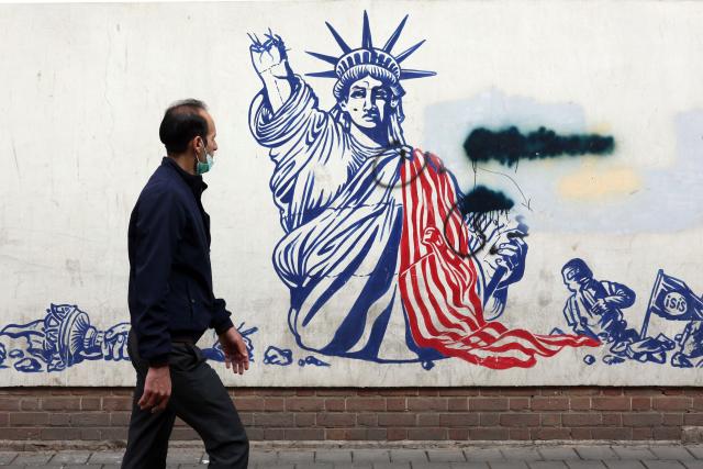 A man walks past a mural depicting the US Statue of Liberty with the torch-bearing arm broken, painted on the outer walls of the former US embassy, in Tehran on February 6, 2026. Iran's Foreign Minister met with his Omani counterpart in Muscat on February 6, ahead of Oman-mediated talks with the United States on the Islamic republic's nuclear programme. (Photo by AFP)