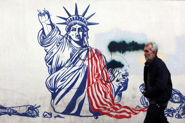 A man walks past a mural depicting the US Statue of Liberty with the torch-bearing arm broken, painted on the outer walls of the former US embassy, in Tehran on February 6, 2026. Iran's Foreign Minister met with his Omani counterpart in Muscat on February 6, ahead of Oman-mediated talks with the United States on the Islamic republic's nuclear programme. (Photo by AFP)