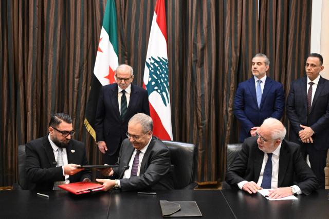 Syria's Justice Minister Mazhar al-Wais (L) and Lebanese Deputy Prime Minister Tarek Metri (R), hand over signed prisoner exchange agreements, as Lebanese Prime Minister Nawaf Salam (Back-C-L) and Lebanese Justice Minister Adel Nassr (R-seated) look on, at the Grand Serail (Government Palace), in Beirut on February 6, 2026. (Photo by JOSEPH EID / AFP)