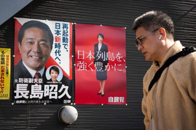 A man walks past posters of Japan's Prime Minister Sanae Takaichi and a candidate running for the upcoming House of Representatives election, in Inagi, Tokyo prefecture on February 6, 2026. (Photo by Yuichi YAMAZAKI / AFP)