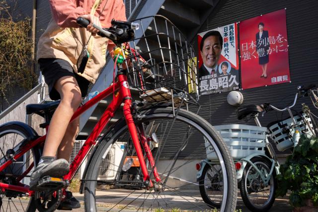 A child cycles past posters of Japan's Prime Minister Sanae Takaichi and a candidate running for the upcoming the House of Representatives election, in Inagi, Tokyo prefecture on February 6, 2026. (Photo by Yuichi YAMAZAKI / AFP)