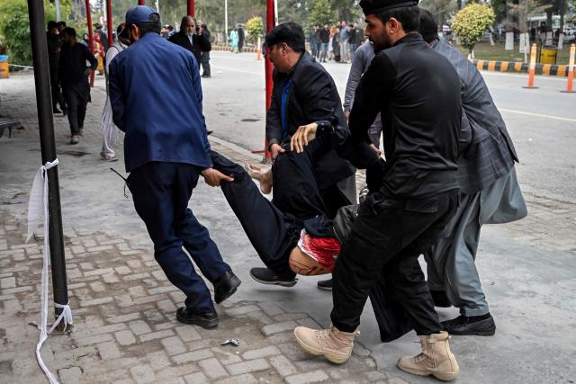 EDITORS NOTE: Graphic content / Policemen shift an injured man to a hospital following an explosion at a mosque in Islamabad on February 6, 2026. A blast at a Shiite mosque in Pakistan's capital Islamabad on February 6 killed 11 people and wounded 20, a police source told AFP. (Photo by Aamir QURESHI / AFP)