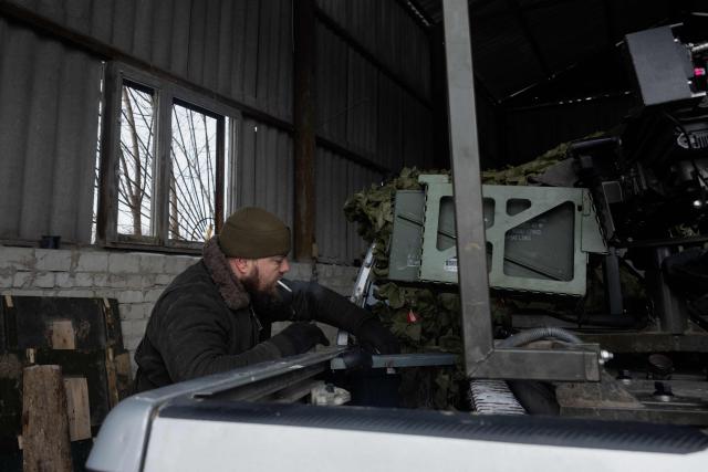 A Ukrainian serviceman of the 30th separate mechanized brigade fixes a robotic combat vehicle armed with an Mk 19 grenade launcher on a military vehicle after testing it at an undisclosed location in Donetsk region on January 27, 2026, amid the Russian invasion of Ukraine. (Photo by Tetiana DZHAFAROVA / AFP)