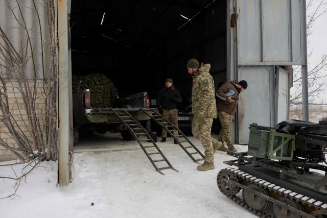Ukrainian servicemen of the 30th separate mechanized brigade load a robotic combat vehicle armed with an Mk 19 grenade launcher onto a military vehicle after testing it at an undisclosed location in Donetsk region on January 27, 2026, amid the Russian invasion of Ukraine. (Photo by Tetiana DZHAFAROVA / AFP)