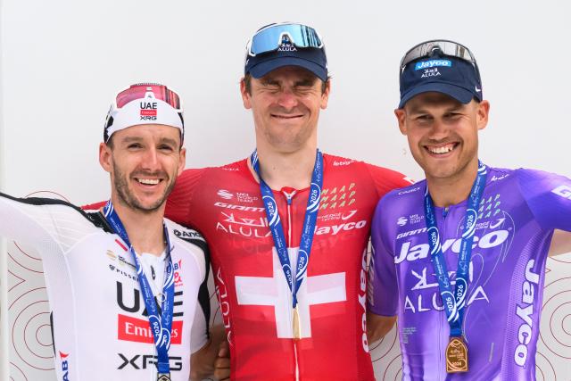 Team Jayco AlUla Swiss rider Mauro Schmid (C) celebrates on the podium after winning the Muscat Classic cycling race, flanked by second placed UAE Team Emirates XRG British rider Adam Yates (L) and third placed Team Jayco AlUla Australian rider Lucas Plapp in Muscat, on February 6, 2026. (Photo by Loic VENANCE / AFP)