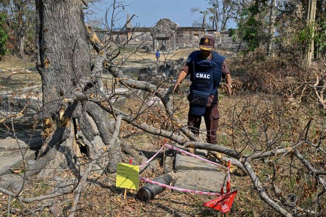 A deminer from the Cambodian Mine Action Centre (CMAC) looks at unexploded ordnance (UXO) at the Preah Vihear temple in Preah Vihear province on February 6, 2026. Chunks of broken sandstone litter Cambodia's UNESCO-listed Preah Vihear temple, whose centuries-old sandstone facades are pocked with fresh shrapnel scars after weeks of deadly border clashes with neighbouring Thailand. Considered a masterpiece of Khmer architecture that looks out over the northern Cambodian plains, the temple became a war zone when a longstanding border dispute erupted into fighting with jets, artillery, tanks and ground troops last year. (Photo by TANG CHHIN Sothy / AFP) / To go with 'CAMBODIA-THAILAND-CONFLICT-HERITAGE, REPORTAGE' by Suy SE