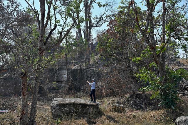 Ea Darith, director of conservation and archeology at the Preah Vihear Authority, takes picture at the Preah Vihear temple in Preah Vihear province on February 6, 2026. Chunks of broken sandstone litter Cambodia's UNESCO-listed Preah Vihear temple, whose centuries-old sandstone facades are pocked with fresh shrapnel scars after weeks of deadly border clashes with neighbouring Thailand. Considered a masterpiece of Khmer architecture that looks out over the northern Cambodian plains, the temple became a war zone when a longstanding border dispute erupted into fighting with jets, artillery, tanks and ground troops last year. (Photo by TANG CHHIN Sothy / AFP) / To go with 'CAMBODIA-THAILAND-CONFLICT-HERITAGE, REPORTAGE' by Suy SE