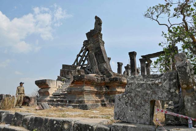 A police officer inspects a damaged section at the Preah Vihear temple in Preah Vihear province on February 6, 2026. Chunks of broken sandstone litter Cambodia's UNESCO-listed Preah Vihear temple, whose centuries-old sandstone facades are pocked with fresh shrapnel scars after weeks of deadly border clashes with neighbouring Thailand. Considered a masterpiece of Khmer architecture that looks out over the northern Cambodian plains, the temple became a war zone when a longstanding border dispute erupted into fighting with jets, artillery, tanks and ground troops last year. (Photo by TANG CHHIN Sothy / AFP) / To go with 'CAMBODIA-THAILAND-CONFLICT-HERITAGE, REPORTAGE' by Suy SE
