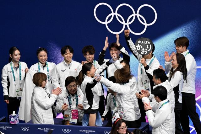 Japan's Kaori Sakamoto (C) reacts with team mates after competing in the figure skating women's single short program team event during the Milano Cortina 2026 Winter Olympic Games at Milano Ice Skating Arena in Milan on February 6, 2026. (Photo by Antonin THUILLIER / AFP)
