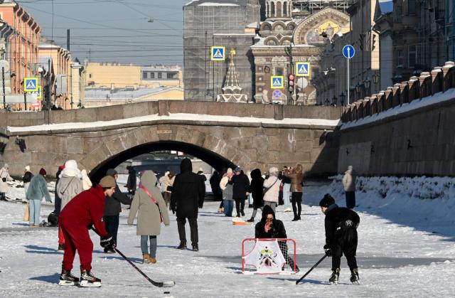 People walk on the frozen Griboyedov Canal in Saint Petersburg on February 6, 2026. (Photo by Olga MALTSEVA / AFP)