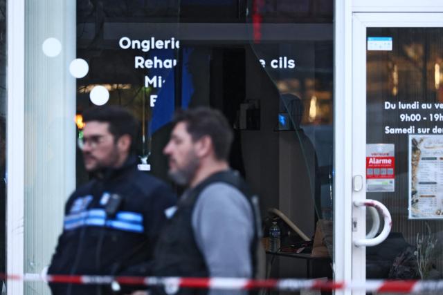 Police officers stand outside a beauty institute that was attacked earlier with a grenade in Grenoble on February 6, 2026. Two individuals presented themselves at the institute, one threw an explosive object that had 'no significant charge or projecting metal elements' and the other filmed the scene, prosecutor Etienne Manteaux explained. Their video is already on social networks, he said, mentioning an 'intimidation action' demonstrating 'an escalation in the delinquency of offenders'. (Photo by Alex MARTIN / AFP)
