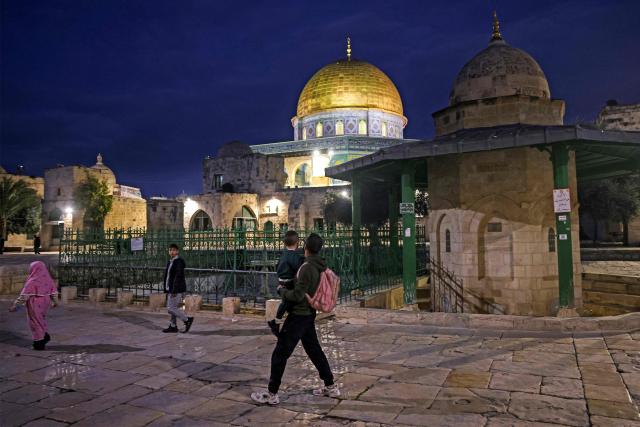 A Palestinian Muslim man walks carrying a child near the Dome of the Rock Shrine at the Aqsa mosque compound in the old city of Jerusalem late on Febuary 6, 2026. (Photo by AHMAD GHARABLI / AFP)