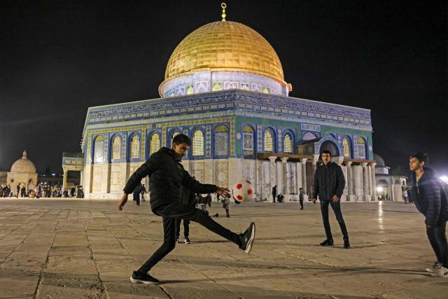 Palestinian youths play with a football outside the Dome of the Rock Shrine at the Aqsa mosque compound in the old city of Jerusalem late on Febuary 6, 2026. (Photo by AHMAD GHARABLI / AFP)