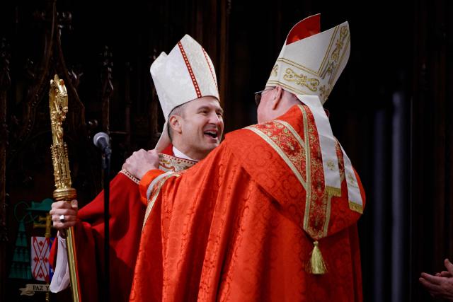 Ronald Hicks (L) is embraced by Cardinal Timothy Doland (R) as Hicks is installed as the 11th Archbishop of New York, suceeding Dolan, during an installation Mass at St. Patrick’s Cathedral in New York on February 6, 2026. (Photo by Leonardo Munoz / AFP)
