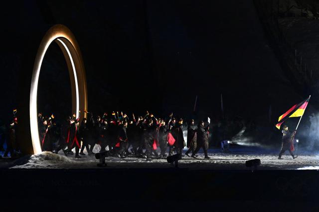 Germany's flag bearer Katharina Schmid (R) and athletes parade during the opening ceremony of the Milano Cortina 2026 Winter Olympic Games at the Predazzo Ski Jumping Stadium in Predazzo (Val di Fiemme), on February 6, 2026. (Photo by Tobias SCHWARZ / AFP)