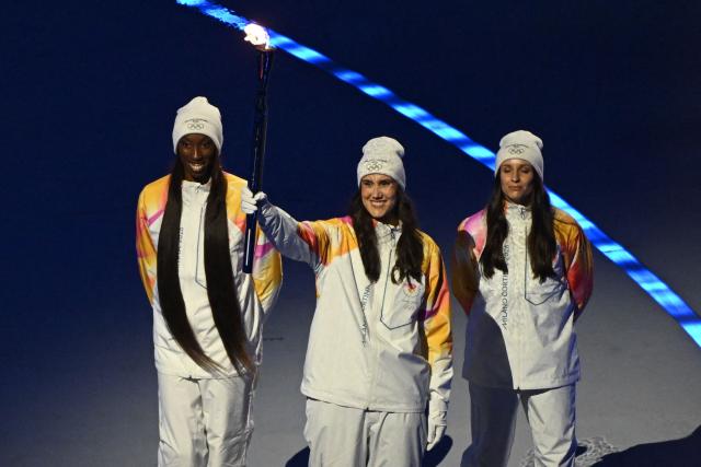 Torchbearers carry the Olympic torch for a symbolic relay during the opening ceremony of the Milano Cortina 2026 Winter Olympic Games at the San Siro stadium in Milan, northern Italy, on February 6, 2026. (Photo by Piero CRUCIATTI / AFP)