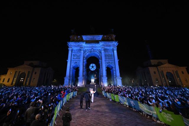 A torchbearer carries the Olympic torch towards the cauldron during the opening ceremony of the Milano Cortina 2026 Winter Olympic Games next to the Arco della Pace monument in Milan, northern Italy, on February 6, 2026. (Photo by JULIEN DE ROSA / AFP)