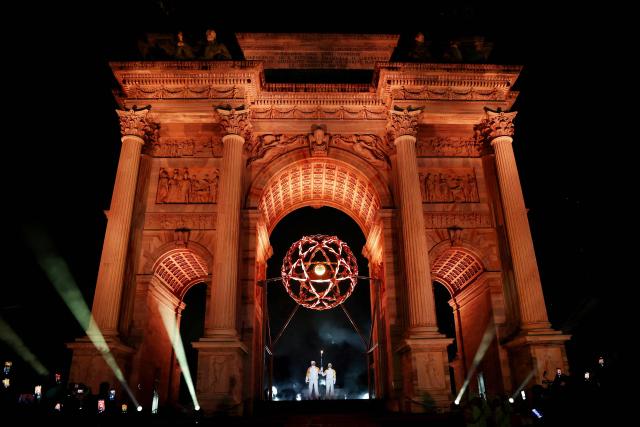 Torchbearers Olympic champions Italy's Deborah Compagnoni and Alberto Tomba look on after lighting the Olympic cauldron at the Arco della Pace (Arch of Peace) outside the San Siro Stadium during the opening ceremony of the Milano Cortina 2026 Winter Olympic Games in Milan, northern Italy, on February 6, 2026. (Photo by Jamie Squire / POOL / AFP)