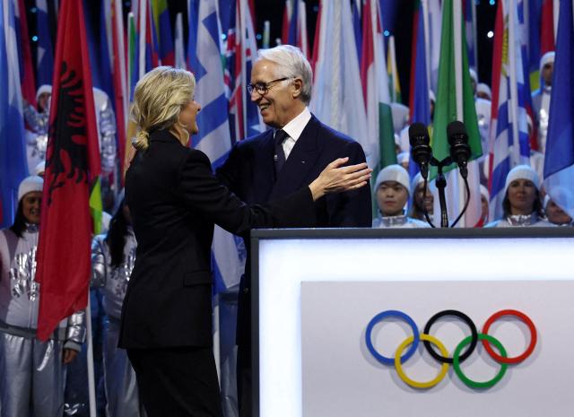 President of the International Olympic Committee (IOC) Kirsty Coventry (L) is welcomed by President of the Organising Committee for the 2026 Olympic and Paralympic Winter Games Giovanni Malago (R) on stage during the opening ceremony of the Milano Cortina 2026 Winter Olympic Games at the San Siro stadium in Milan, northern Italy, on February 6, 2026. (Photo by Yves Herman / POOL / AFP)