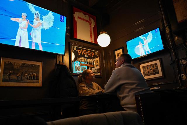 People watch the live TV broadcast of the Milano Cortina 2026 Winter Olympic Games opening ceremony at a bar in central Moscow, on February 6, 2026. (Photo by HECTOR RETAMAL / AFP)