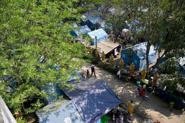 People, displaced after clashes between Thai and Cambodian soldiers, walk past tents in an evacuation centre on the grounds of a pagoda in Banteay Meanchey province on February 4, 2026. A sign hanging from a rusty ice-green shipping container installed by Thai forces on what they say is the border with Cambodia proclaims: "Cambodian citizens are strictly prohibited from entering this area." (Photo by TANG CHHIN Sothy / AFP) / To go with 'THAILAND-CAMBODIA-CONFLICT-BORDER,REPORTAGE' by Suy SE and Montira RUNGJIRAJITTRANON