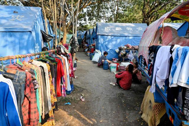 People, displaced after clashes between Thai and Cambodian soldiers, sit beside tents in an evacuation centre on the grounds of a pagoda in Banteay Meanchey province on February 4, 2026. A sign hanging from a rusty ice-green shipping container installed by Thai forces on what they say is the border with Cambodia proclaims: "Cambodian citizens are strictly prohibited from entering this area." (Photo by TANG CHHIN Sothy / AFP) / To go with 'THAILAND-CAMBODIA-CONFLICT-BORDER,REPORTAGE' by Suy SE and Montira RUNGJIRAJITTRANON