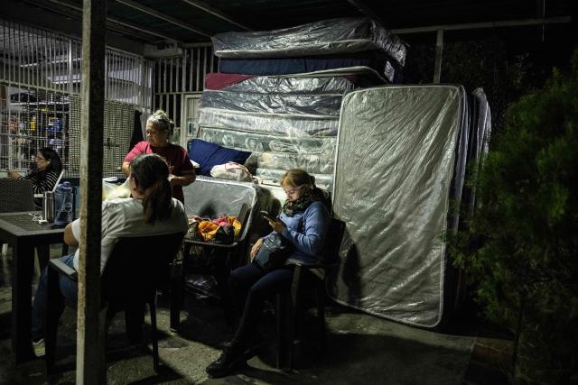 A woman watches her mobile phone as she camps outside El Rodeo I prison as they wait for news of prisoner releases in Guatire, Miranda state, some 30 kilometers east of Caracas, on February 6, 2026. Venezuela's parliament chief, a former member of ousted leader Nicolas Maduro's inner circle, on February 6 promised the speedy release of remaining political prisoners during a meeting with their relatives. "By Friday (February 13) at the latest they will all be free," Jorge Rodriguez told prisoners' families outside the notorious Zona 7 detention center in Caracas. (Photo by Maryorin Mendez / AFP)