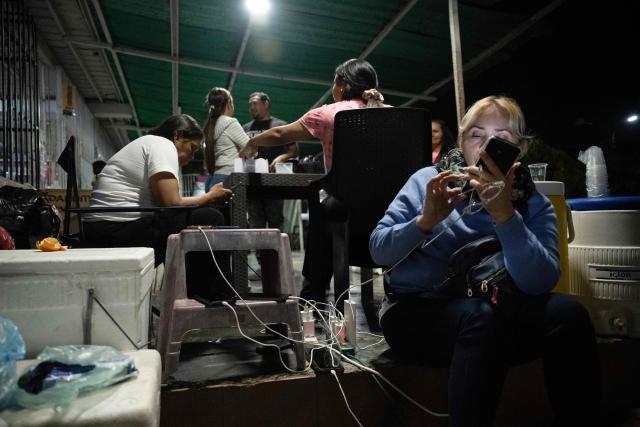 A woman watches her mobile phone as she camps outside El Rodeo I prison as they wait for news of prisoner releases in Guatire, Miranda state, some 30 kilometers east of Caracas, on February 6, 2026. Venezuela's parliament chief, a former member of ousted leader Nicolas Maduro's inner circle, on February 6 promised the speedy release of remaining political prisoners during a meeting with their relatives. "By Friday (February 13) at the latest they will all be free," Jorge Rodriguez told prisoners' families outside the notorious Zona 7 detention center in Caracas. (Photo by Maryorin Mendez / AFP)
