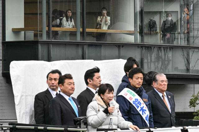 People in a building opposite to Rekisen Park take pictures of Japan's Prime Minister and President of the Liberal Democratic Party (LDP) Sanae Takaichi (C) as she delivers a campaign speech ahead of the House of Representatives election in Tokyo on February 7, 2026. (Photo by Philip FONG / AFP)