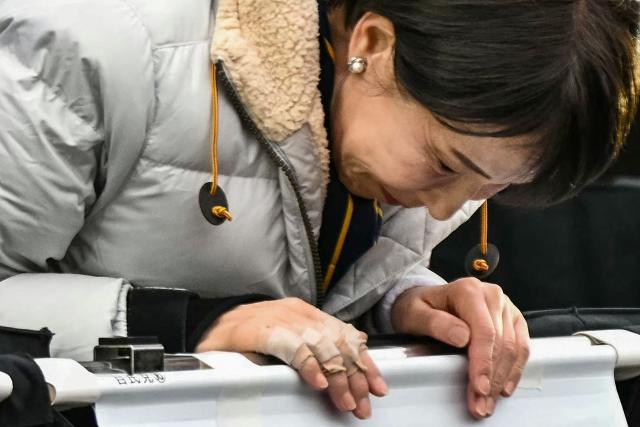 TOPSHOT - The bandaged injured hand of Japan's Prime Minister and President of the Liberal Democratic Party (LDP) Sanae Takaichi is seen as she bows to the crowd upon her arrival to deliver a campaign speech ahead of the House of Representatives election, at Rekisen Park in Tokyo on February 7, 2026. (Photo by Philip FONG / AFP)