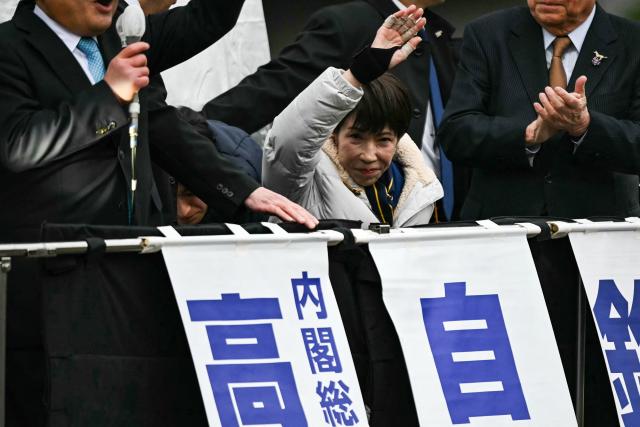 People in a building opposite to Rekisen Park take pictures of Japan's Prime Minister and President of the Liberal Democratic Party (LDP) Sanae Takaichi (C) waves to the crowd as she prepares to leave after she delivered a campaign speech ahead of the House of Representatives election in Tokyo on February 7, 2026. (Photo by Philip FONG / AFP)