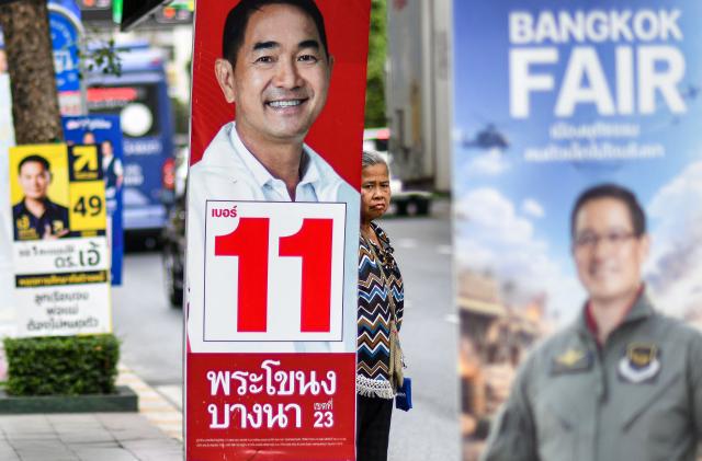 A pedestrian waits at a bus stop between campaign posters on the eve of Thailand's general election in Bangkok on February 7, 2026. (Photo by Amaury PAUL / AFP)