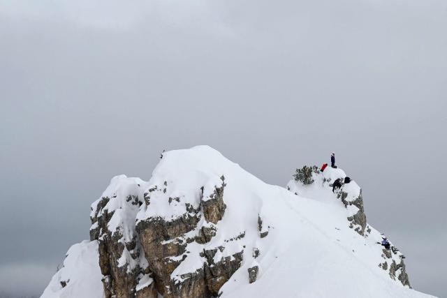 A coach stands on the top of a peak to watch the official training for the women's downhill event during the Milano Cortina 2026 Winter Olympic Games at the Tofane Alpine Skiing Centre in Cortina d’Ampezzo on February 7, 2026. (Photo by Stefano RELLANDINI / AFP)
