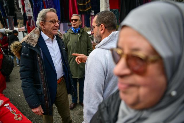 Mayor of Grenoble and Les Republicains' lead candidate for his re-election, Alain Carignon (L) speaks with a local resident as he distributes campaign leaflets at the market in Grenoble on February 7, 2026. (Photo by OLIVIER CHASSIGNOLE / AFP)