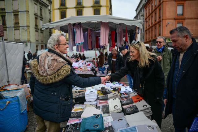 Mayor of Grenoble and Les Republicains' lead candidate for his re-election, Alain Carignon (L) distributes campaign leaflets to local residents at the market in Grenoble on February 7, 2026. (Photo by OLIVIER CHASSIGNOLE / AFP)