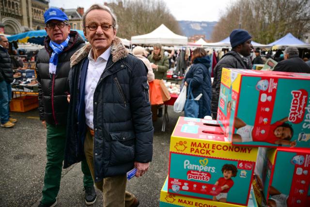 Mayor of Grenoble and Les Republicains' lead candidate for his re-election, Alain Carignon (R) walks through a local market as he distributes campaign leaflets in Grenoble on February 7, 2026. (Photo by OLIVIER CHASSIGNOLE / AFP)