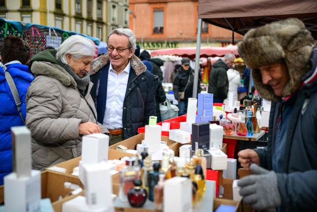 Mayor of Grenoble and Les Republicains' lead candidate for his re-election, Alain Carignon (C) speaks with a local resident as he distributes campaign leaflets at the market in Grenoble on February 7, 2026. (Photo by OLIVIER CHASSIGNOLE / AFP)