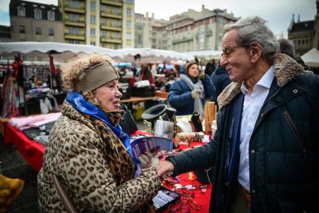 Mayor of Grenoble and Les Republicains' lead candidate for his re-election, Alain Carignon (R) speaks with a local resident as he distributes campaign leaflets at the market in Grenoble on February 7, 2026. (Photo by OLIVIER CHASSIGNOLE / AFP)