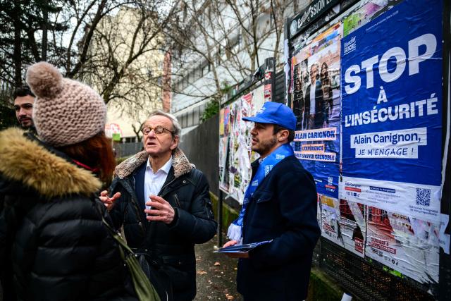 Mayor of Grenoble and Les Republicains' lead candidate for his re-election, Alain Carignon (C) speaks with a local resident as he distributes campaign leaflets at a market in Grenoble on February 7, 2026. (Photo by OLIVIER CHASSIGNOLE / AFP)