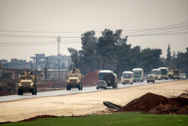 US military vehicles move along a road in a convoy transporting Islamic State group detainees being transferred to Iraq from Syria, on the outskirts of Qahtaniyah in Syria's northeastern Hasakah province on February 7, 2026. Iraq's judiciary announced on February 2 that it had begun investigations into more than 1,300 Islamic State group detainees who were transferred from Syria as part of a US operation. (Photo by Delil SOULEIMAN / AFP)