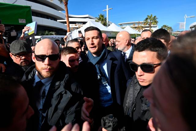 President of French far-right Rassemblement National (RN) party and Member of the European Parliament Jordan Bardella (C) arrives at the Cap d'Agde market in support of Aurélien Lopez-Liguori, lead candidate in the Agde municipal elections, in Cap d'Agde, southern France on February 7, 2026. (Photo by Sylvain THOMAS / AFP)