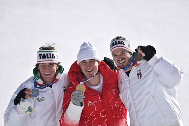 Gold medallist Switzerland's Franjo von Allmen (C), silver medallist Italy's Giovanni Franzoni (L) and bronze medallist Italy's Dominik Paris (R) pose on the podium after the men's downhill alpine skiing event during the Milano Cortina 2026 Winter Olympic Games at the Stelvio Ski Centre in Bormio (Valtellina) on February 7, 2026. (Photo by Jeff PACHOUD / AFP)